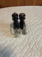 All six shakers and grinders displayed together on a quilted surface