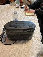 Top and side view of Sony clock radio cassette player showing controls and attached power cord
