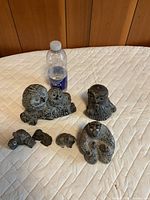 Overview of six stone animal figurines with water bottle for scale