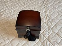 closed wooden ring box showing exterior finish, clasp and tassel