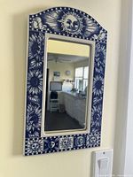 Front view of blue and white ceramic wall mirror hanging on wall