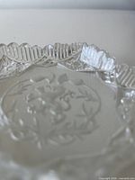 oblique view of coaster showing scalloped rim and etched motif