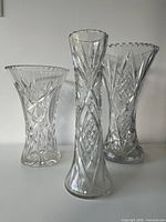 Three clear cut crystal vases standing side-by-side