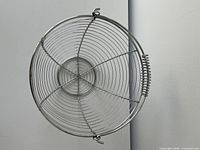 Top view of round chrome-plated wire basket showing spiral bottom and handle spring