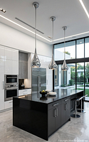 Staged kitchen scene showing three installed Aura Teardrop chrome pendants over island