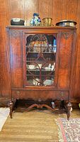 Front view of closed oak china cabinet showing carved details and glass doors