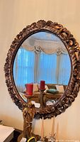 Front view of ornate gold oval mirror on wall