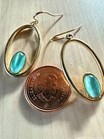 Front view of both earrings beside Canadian cent for scale
