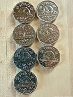 Front (reverse) view of seven Canadian 5-cent coins showing beaver and refinery designs with visible years