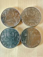 Obverse sides of four Canadian $1 coins showing years 1979, 1983, 1984 and Jacques Cartier 1984