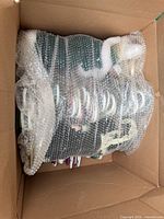 Box containing numerous garments on hangers wrapped in bubble wrap