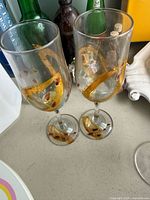 Two champagne flutes with gold and red swirl design