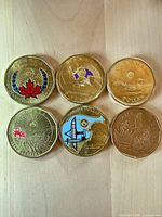 Fronts of six Canadian $1 coins showing coloured commemorative designs