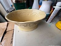 Oblique view of cream footed bowl showing overall shape and vine relief