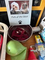 All items grouped: bowl with collar inside, green chew toys, waste-bag dispenser, water spout, dental pack, photo frame