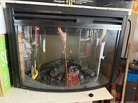 Front view of electric fireplace insert showing curved glass and log bed