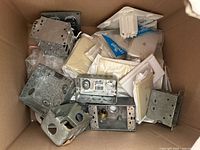 Cardboard box containing assorted metal electrical boxes and packaged wall plates