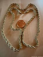 Full view of gold tone rope chain with coin for scale