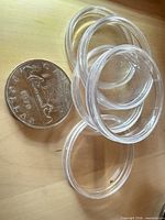 Clear plastic coin capsules beside Canadian dollar coin for scale
