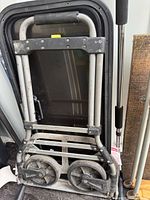 full view of folded aluminum hand truck leaning against wall
