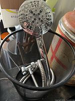 Shower wand with hose inside black mesh wastebasket