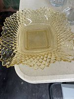 Top view of square amber pressed glass dish showing pinwheel pattern and sawtooth rim