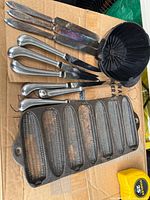 All items grouped: 3 silver knives, 6 stainless knives, cast iron pan, coffee cone