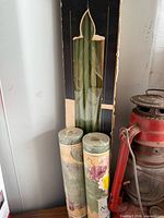 Box of green tapers beside two wallpaper border rolls