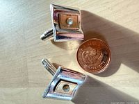Front view showing silver border, gold inset, white center, penny for scale