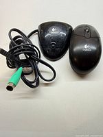 Logitech receiver base with wired PS/2 connector beside cordless mouse