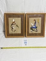 Front view of both framed paintings with measuring tape for scale