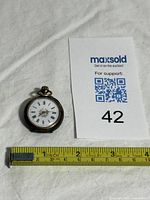 Pocket watch next to tape measure showing scale
