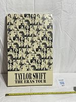 Front of collectors box with collage graphics and tour title, tape measure for size reference
