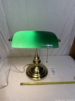 Full view of brass base bankers lamp with green glass shade and pull chain