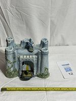 Front view of ceramic castle music box with drawbridge lowered, ruler for scale