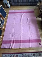 Full view of unfolded pink wool blanket showing size and end bands
