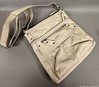 Front view of beige leather crossbody bag with strap and front zip pocket
