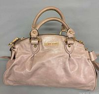Front view of blush-taupe Miu Miu Vitello Lux handbag showing logo, handles, zip top and hardware