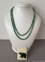 Necklace displayed double-wrapped on bust with jade bear brooch