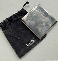 Closed Decubal compact mirror resting on velvet pouch