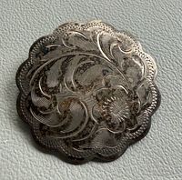 Front view of sterling silver scalloped brooch showing floral engraving