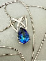 Front view of pendant showing faceted multicolour gemstone and silver ribbon setting