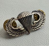 Front view of sterling silver parachutist badge with brass clutches attached