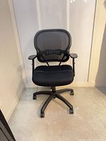 Front view of black mesh back office chair showing seat, armrests and base