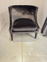 Front view of black velvet accent chair showing tufted back, nailhead trim, seat cushion, and wood legs