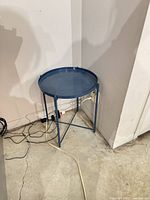 Full view of blue metal side table in corner