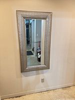 Front view of the wall mirror hung on wall, showing full frame and glass