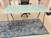 Full view of desk showing frosted glass top and chrome legs