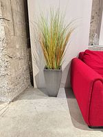 Planter with artificial grass placed next to a red sofa for scale