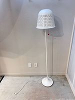 Full view of white metal floor lamp standing on floor